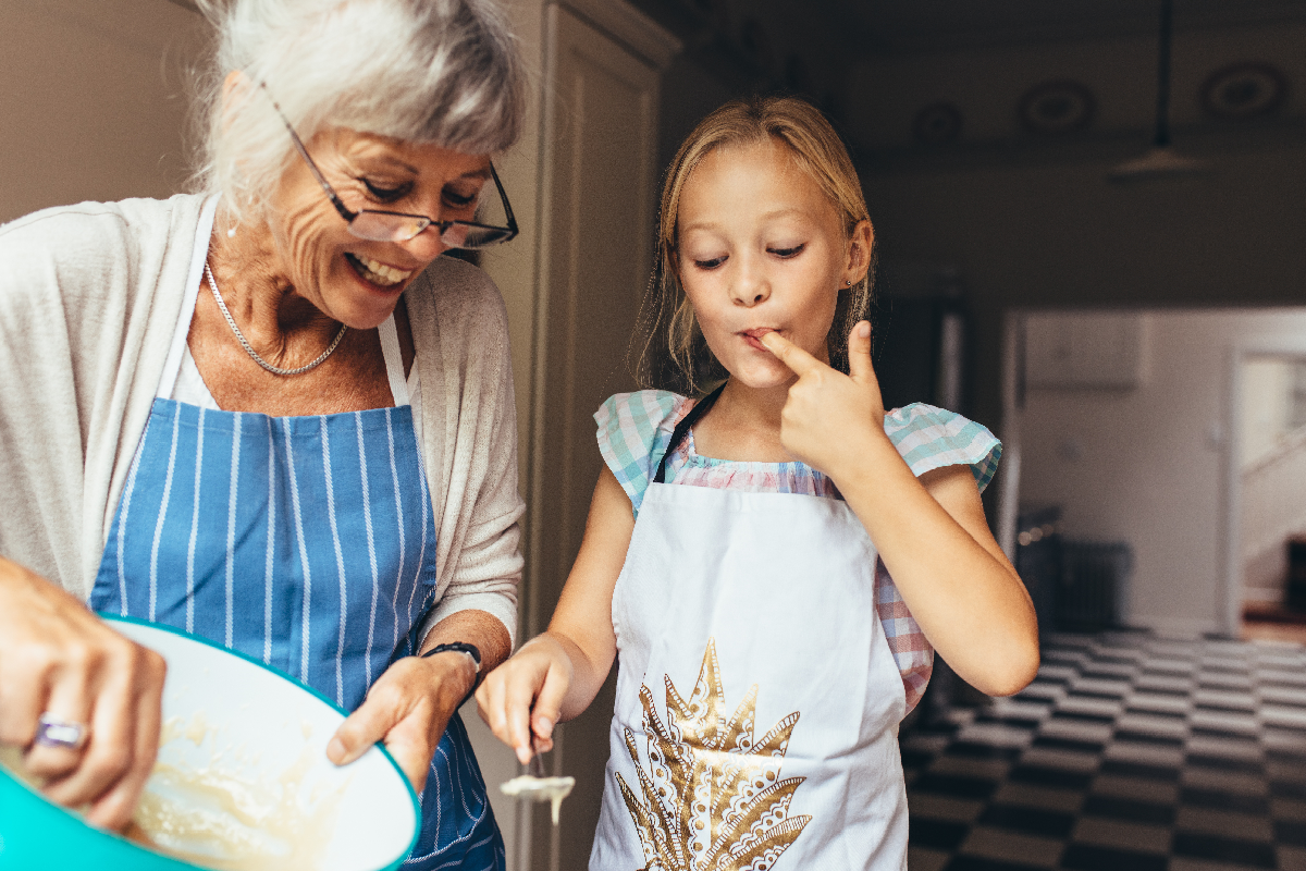 Großmutter und Enkeltochter backen und probieren den Teig